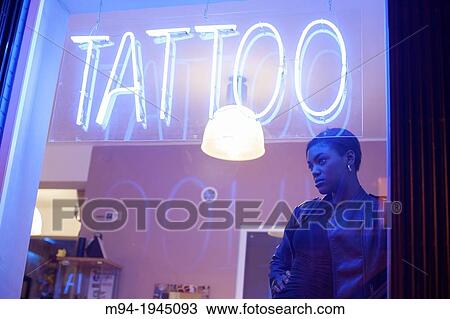 Stock Image - Black woman in a tattoo studio.. Fotosearch