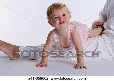 Blond little girl climbing on her mothers legs View Large Photo Image Stock Image - Blond little girl climbing on her mothers legs. Fotosearch