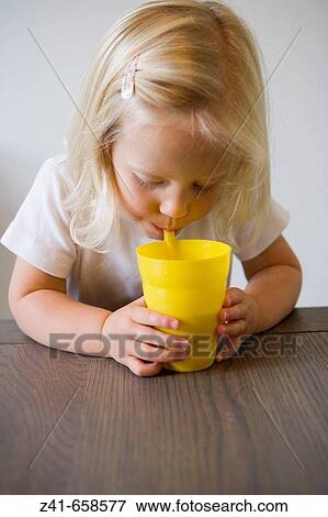 Blond little girl is drinking from a yellow cup View Large Photo Image Stock Photo - Blond little girl is drinking from a yellow cup. Fotosearch