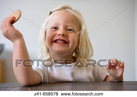 Blond little girl is is eating a coockie View Large Photo Image Stock Photo - Blond little girl is is eating a coockie. Fotosearch
