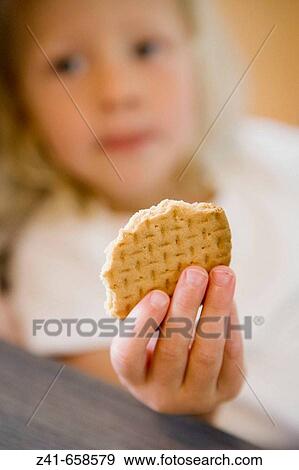 Blond little girl is is eating a coockie View Large Photo Image Stock Photo - Blond little girl is is eating a coockie. Fotosearch
