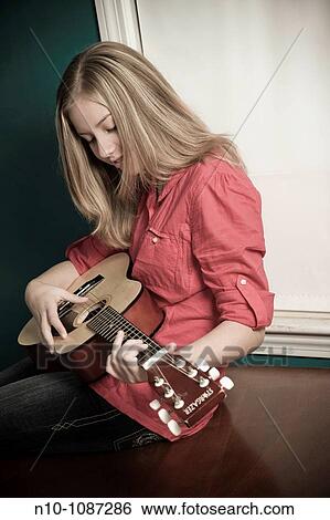 Blond preteen girl playing a guitar View Large Photo Image Stock Photograph - Blond preteen girl playing a guitar. Fotosearch