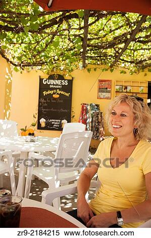 Blond smiling woman waiting for lunch at an outdoor cafe, Barrydale, Little Karoo, South Africa. View Large Photo Image Stock Photography - Blond smiling woman waiting for lunch at an outdoor cafe, Barrydale, Little Karoo, South Africa.. Fotosearch