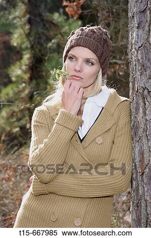 Blond woman in her 20's 30's folding her arms in front of her chest looking sad in a forest holding some grass by her mouth View Large Photo Image Stock Photography - Blond woman in her 20's 30's folding her arms in front of her chest looking sad in a forest holding some grass by her mouth. Fotosearch
