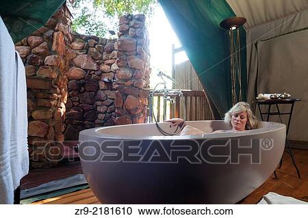 Blond woman naps inside a large oval bathtub in a luxury safari tent, Botlierskop Game Lodge, Mosselbay, South Africa. View Large Photo Image Stock Image - Blond woman naps inside a large oval bathtub in a luxury safari tent, Botlierskop Game Lodge, Mosselbay, South Africa.. Fotosearch