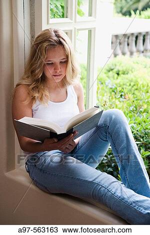 Blonde barefoot teen girl sits by an open window reading a book. View Large Photo Image Stock Image - Blonde barefoot teen girl sits by an open window reading a book.. Fotosearch