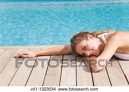 Picture - Blonde beautiful woman resting and lying down by the pool. Fotosearch