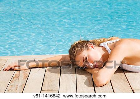 Stock Image - Blonde beautiful woman resting and lying down by the pool. Fotosearch