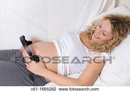 Blonde beuatiful pregnant woman lying down in sofa with earphones in Belly View Large Photo Image Stock Image - Blonde beuatiful pregnant woman lying down in sofa with earphones in Belly. Fotosearch