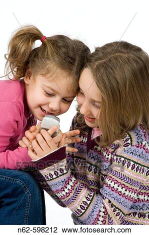 Stock Image - Blonde girls looking at their cell phone. Fotosearch