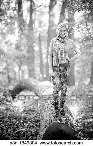 Blonde haired woman outdoors on log View Large Photo Image Picture - Blonde haired woman outdoors on log. Fotosearch