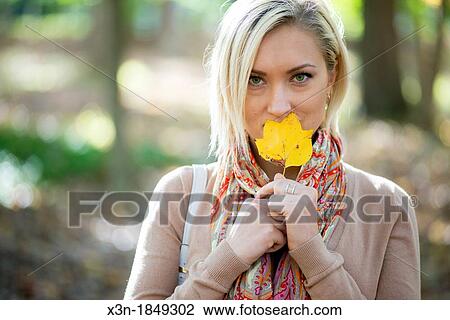 Blonde haired woman outdoors with yellow leaf View Large Photo Image Stock Image - Blonde haired woman outdoors with yellow leaf. Fotosearch