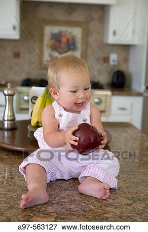 Blonde infant girl holding an apple. View Large Photo Image Stock Photo - Blonde infant girl holding an apple.. Fotosearch