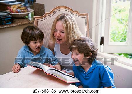 Stock Photography - Blonde older sister reads book to her two younger fair haired brothers.. Fotosearch