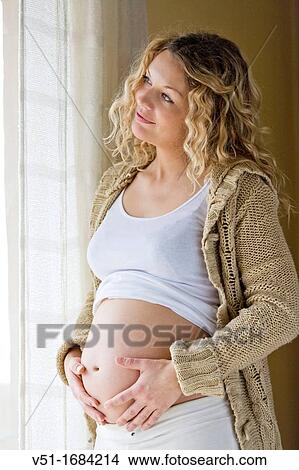 Blonde pregnant woman at home looking at outside View Large Photo Image Picture - Blonde pregnant woman at home looking at outside. Fotosearch