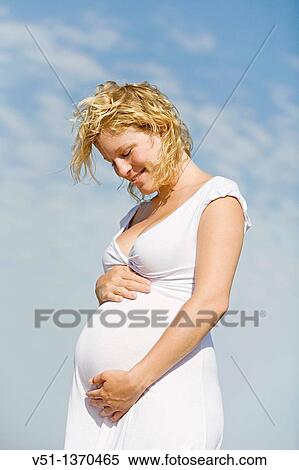 Stock Photography - Blonde pregnant woman enjoying her pregnancy at the beach. Fotosearch