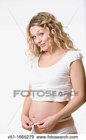 Blonde pregnant woman measuring her belly View Large Photo Image Stock Photo - Blonde pregnant woman measuring her belly. Fotosearch