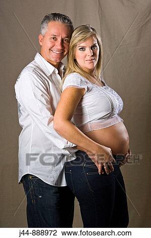 Blonde pregnant woman wearing white standing with man behind her, smiling, portrait View Large Photo Image Stock Image - Blonde pregnant woman wearing white standing with man behind her, smiling, portrait. Fotosearch