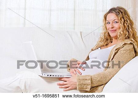 Blonde pregnant woman with laptop on the couch smiling at camera View Large Photo Image Stock Image - Blonde pregnant woman with laptop on the couch smiling at camera. Fotosearch
