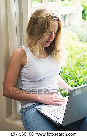 Blonde teen girl sits by an open window using her laptop computer. View Large Photo Image Stock Photo - Blonde teen girl sits by an open window using her laptop computer.. Fotosearch