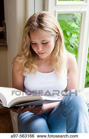 Blonde teen girl sits by an open window reading a book. View Large Photo Image Stock Photograph - Blonde teen girl sits by an open window reading a book.. Fotosearch