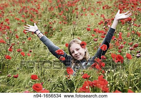 Picture - Blonde teen girl throwing flowers in the wind.. Fotosearch