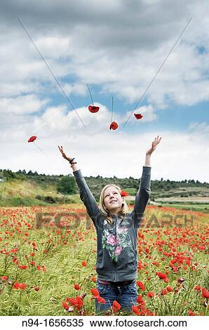 Stock Photography - Blonde teen girl throwing flowers in the wind.. Fotosearch