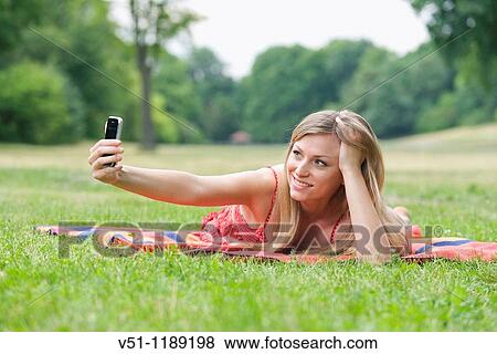 Blonde woman doing a self portrait in the park View Large Photo Image Stock Photo - Blonde woman doing a self portrait in the park. Fotosearch