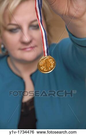 Blonde woman holding a 1st Place medal View Large Photo Image Stock Photograph - Blonde woman holding a 1st Place medal. Fotosearch