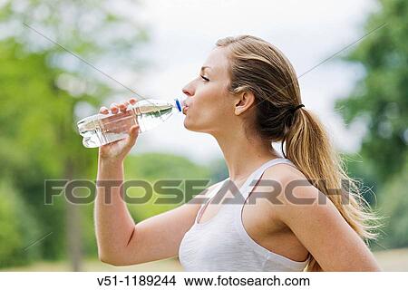 Blonde woman jogging in the park and drinking water View Large Photo Image Picture - Blonde woman jogging in the park and drinking water. Fotosearch