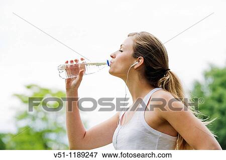 Blonde woman jogging in the park and drinking water View Large Photo Image Stock Photo - Blonde woman jogging in the park and drinking water. Fotosearch