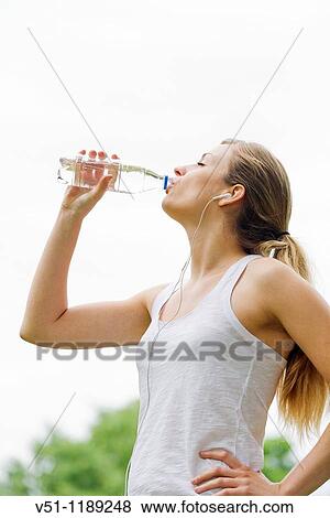 Blonde woman jogging in the park and drinking water View Large Photo Image Stock Photo - Blonde woman jogging in the park and drinking water. Fotosearch