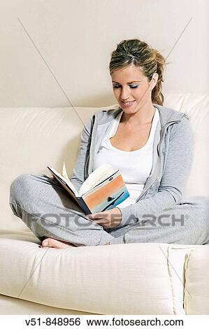 Blonde woman reading a book at home in the couch View Large Photo Image Stock Photograph - Blonde woman reading a book at home in the couch. Fotosearch