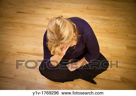 Stock Photograph - Blonde woman sitting on the floor. Fotosearch