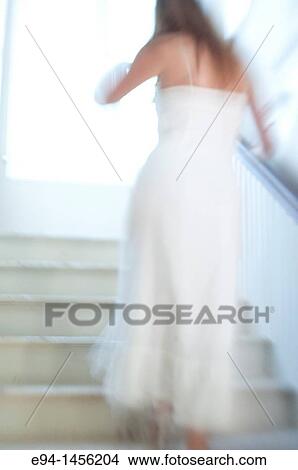 Blurry back view of a woman in a white dress walking up a stairway, indoors View Large Photo Image Picture - Blurry back view of a woman in a white dress walking up a stairway, indoors. Fotosearch