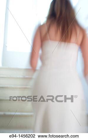 Blurry back view of a woman in a white dress walking up a stairway, indoors View Large Photo Image Stock Image - Blurry back view of a woman in a white dress walking up a stairway, indoors. Fotosearch