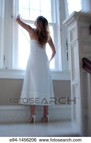 Blurry back view of a woman in a white dress looking out of a window View Large Photo Image Stock Photograph - Blurry back view of a woman in a white dress looking out of a window. Fotosearch