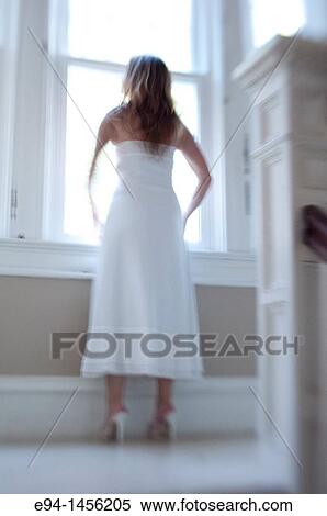 Blurry back view of a woman in a white dress looking out of a window View Large Photo Image Stock Photography - Blurry back view of a woman in a white dress looking out of a window. Fotosearch