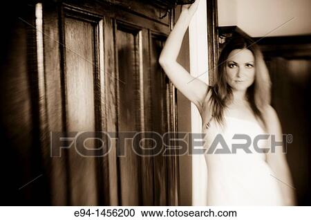 Stock Image - Blurry portrait of a woman in a white dress inside of a home. Fotosearch