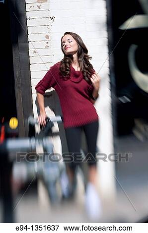 Stock Photo - Blurry portrait of a young brunette woman in a red sweater smiling with eyes closed, face tilted up toward the sun. Fotosearch