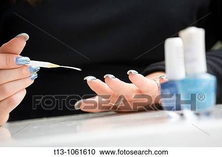 Stock Image - Blushing her hand nails. Fotosearch