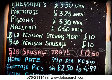 Stock Photo - Board announcing a butcher selling Pheasants, Partridge, Pigeon? s, Mallard, Venisson, Sausage, Home Pate, Cottage Pies. Yorkshire Dales, England, UK, Europe.. Fotosearch