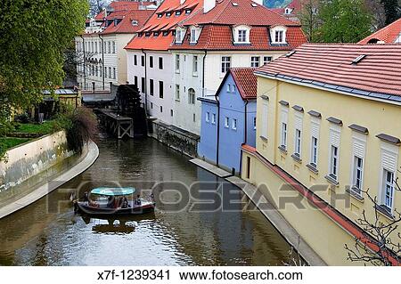Stock Image - boat in Certovka Devil's canal In background water wheel of Great Prior's Mill In Kampa Island MalB Strana quarter Prague Czech Republic. Fotosearch