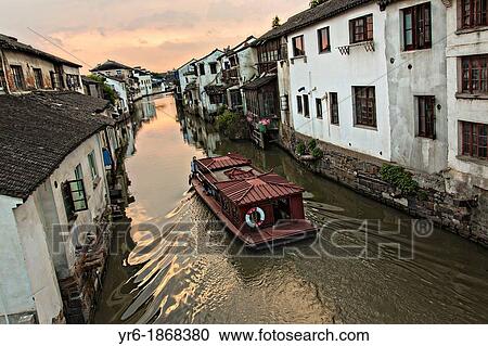 Stock Image - Boat travels along Shantang canal in Suzhou, China. Fotosearch