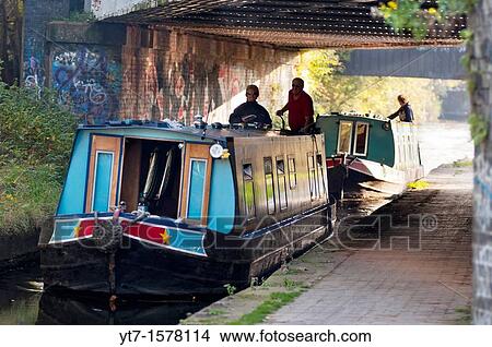 Picture - Boats go under a railway bridge on the Birmingham & Worcester canal at Selly Oak, Birmingham, UK. Fotosearch