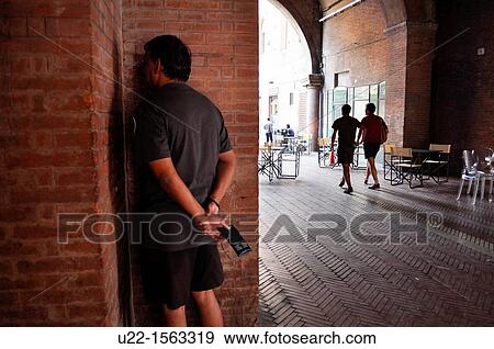 Stock Photo - Bologna (Italy): an Indian tourist playing with the peculiar acoustic effect at one of the four corners of the Voltone del Podest?. Fotosearch