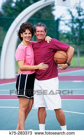 Stock Image - boomer couple on basketball court. Fotosearch