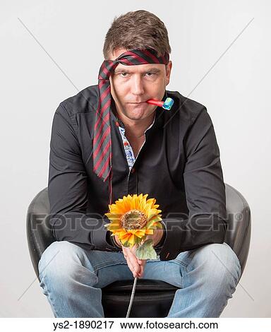 Bored businessman looking depressed at party Sitting in armchair holding a plastic flower and wearing the tie on his forehead View Large Photo Image Stock Photo - Bored businessman looking depressed at party Sitting in armchair holding a plastic flower and wearing the tie on his forehead. Fotosearch