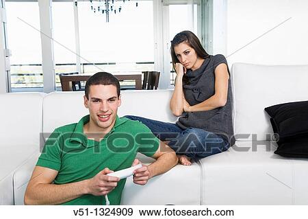 Bored woman looking at her immature boyfriend playing video games View Large Photo Image Stock Photo - Bored woman looking at her immature boyfriend playing video games. Fotosearch