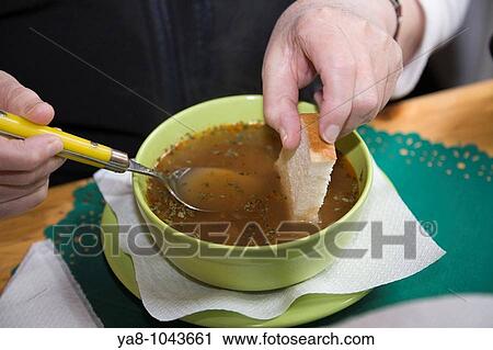 Bowl of brown soup on a table with woman dipping piece of white bread MR 08/16 View Large Photo Image Stock Image - Bowl of brown soup on a table with woman dipping piece of white bread MR 08/16. Fotosearch